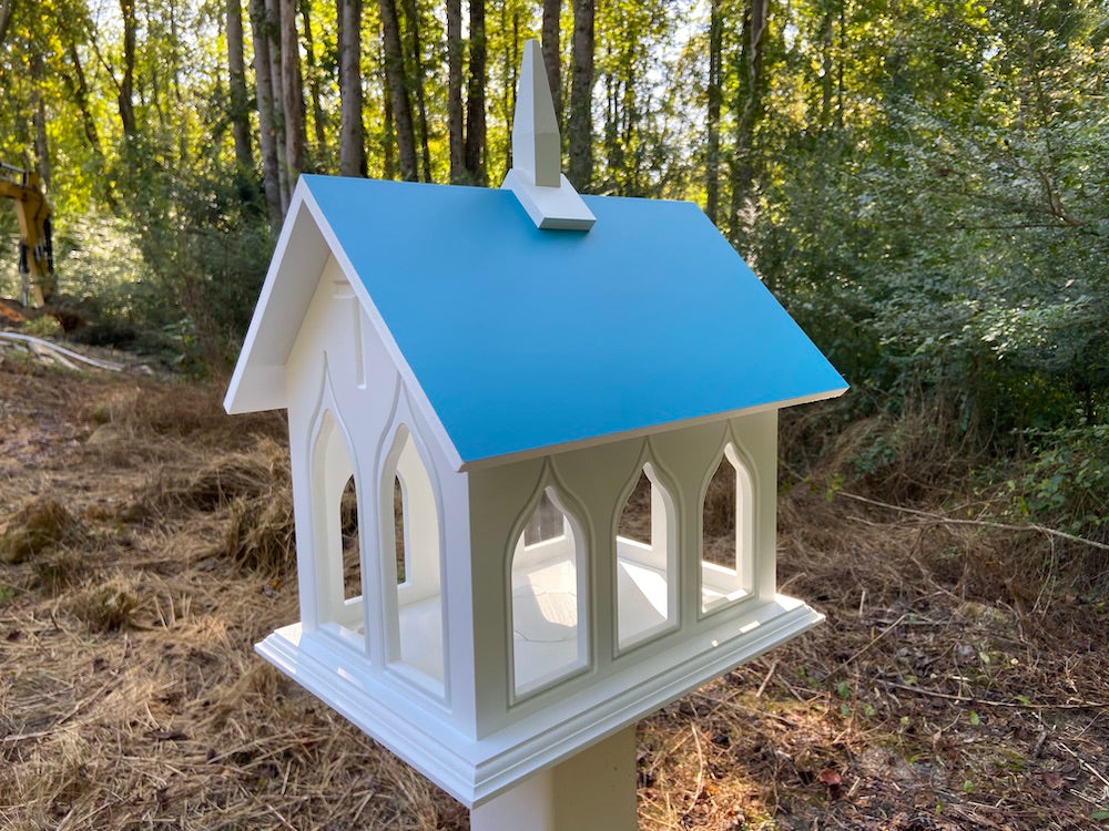 Lagoon blue chapel bird feeder mounted on white post with woods in the background